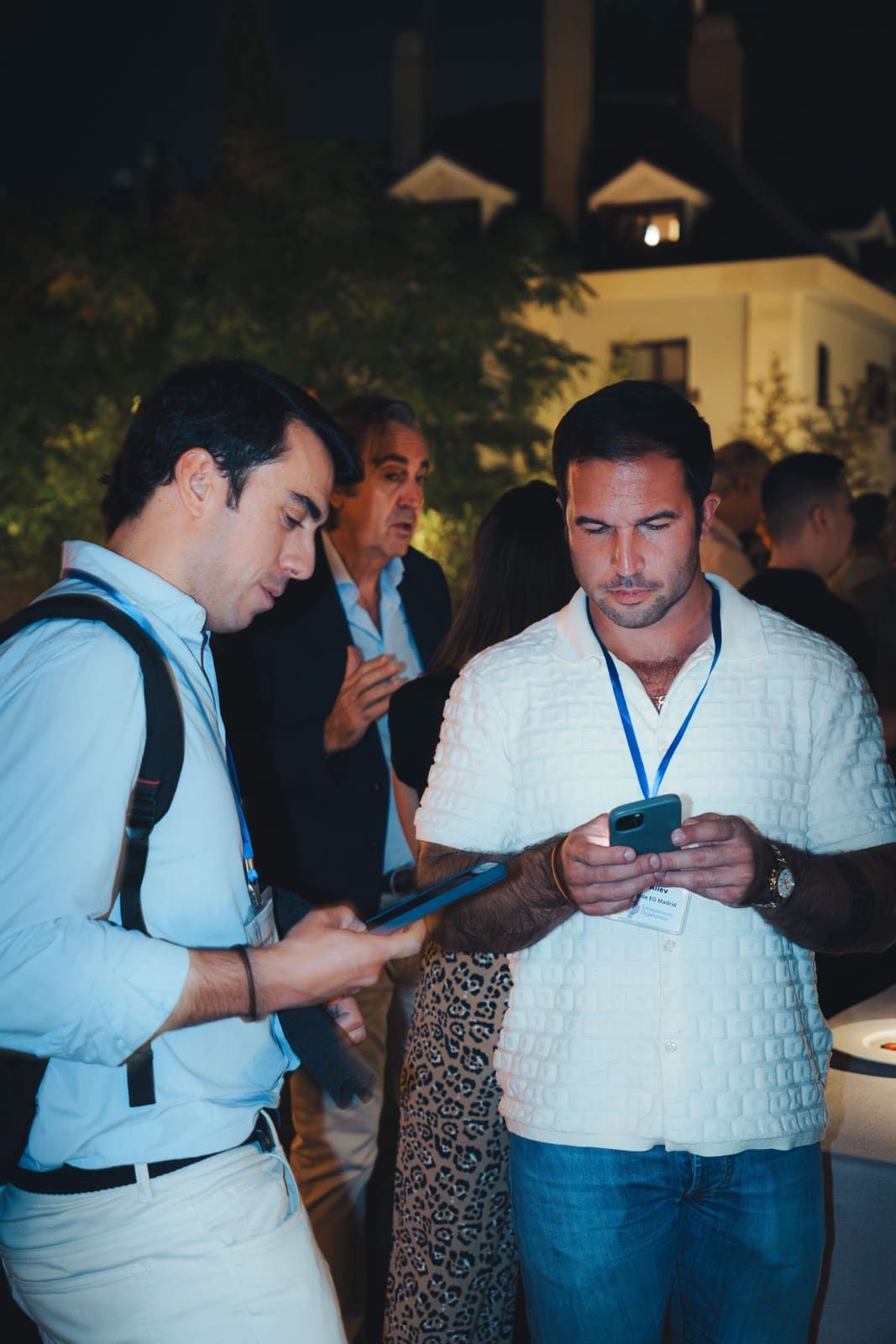 Dos asistentes intercambiando el contacto con el móvil